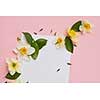 Greeting card with flowers and leaves on a pink background a sheet of paper under the text. Flat lay