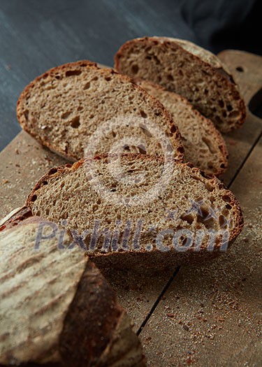 Sliced rye bread on cutting board closeup. The cut rye bread on wooden board brown. Healthy food. Proper nutrition. Bakery. Sliced rye bread on cutting board closeup. The cut rye bread on wooden board brown. Healthy food. Proper nutrition. Bakery.