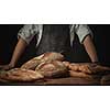 Baker with fresh bread on wooden brown table background