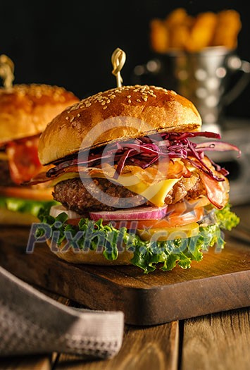 Delicious fresh burger with meat, bacon, cheese and vegetables on a wooden board, in a rustic soul style Delicious fresh burger with meat, bacon, cheese and vegetables on a wooden board, in a rustic soul style