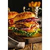 Delicious fresh burger with meat, bacon, cheese and vegetables on a wooden board, in a rustic soul style