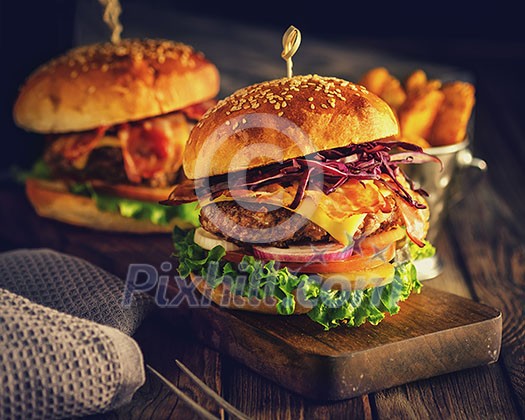 Delicious homemade hamburger on wooden background. Rustic style. Retro toned. Delicious homemade hamburger on wooden background. Rustic style. Retro toned.