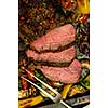 Sliced Grilled Beef rump steak on Baking tray with vegetables. Top view. Closeup.