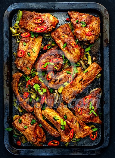 Roasted sliced barbecue pork ribs seasoned with a spicy basting sauce on the baking tray Roasted sliced barbecue pork ribs seasoned with a spicy basting sauce on the baking tray