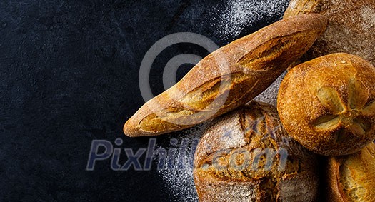 Top view of composition with fresh homemade bread over dark table. Horizontal banner.