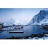 Cold and snowy winter morning in Hamnoy, with houses, boats and mountains.