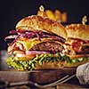 Delicious fresh burger with meat, bacon, cheese and vegetables on a wooden board, in a rustic soul style. Retro vintage toned image.