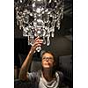 Pretty, young woman choosing the right chandelier for her appartment in a modern home furnishings store (color toned image; shallow DOF)