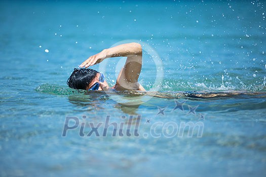 Young man swimming the front crawl in the sea (swimmer, triathlon)