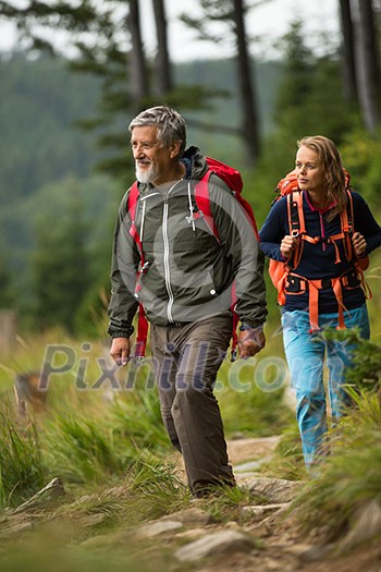 Active senior hiking in high mountains with his daughter