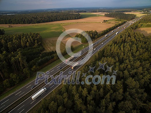 Aerial view of a highway amid fields with cars on it