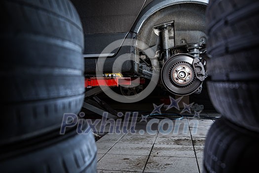 Inside a garage - modern car waiting for the mechanic to change its wheels/tires (shallow DOF; color toned image) Inside a garage - modern car waiting for the mechanic to change its wheels/tires (shallow DOF; color toned image)