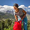 Pretty, female hiker in high mountains packing her backpack