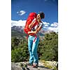 Pretty, female hiker in high mountains packing her backpack