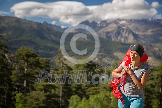 Pretty, female hiker in high mountains packing her backpack