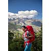 Pretty, female hiker in high mountains packing her backpack