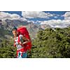 Pretty, female hiker in high mountains packing her backpack