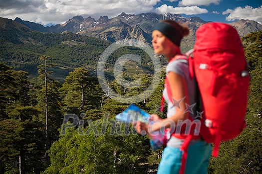 Pretty, female hiker in high mountains packing her backpack Pretty, female hiker in high mountains packing her backpack