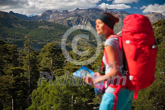 Pretty, female hiker in high mountains packing her backpack