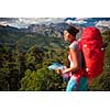 Pretty, female hiker in high mountains packing her backpack