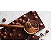 wooden spoon with chocolate and chocolate balls on a white marble background