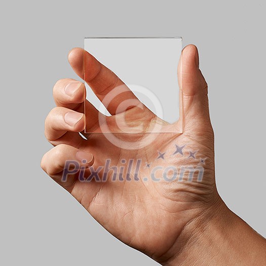 closeup of a transparent glass in a man's hands on a gray background copy space for text