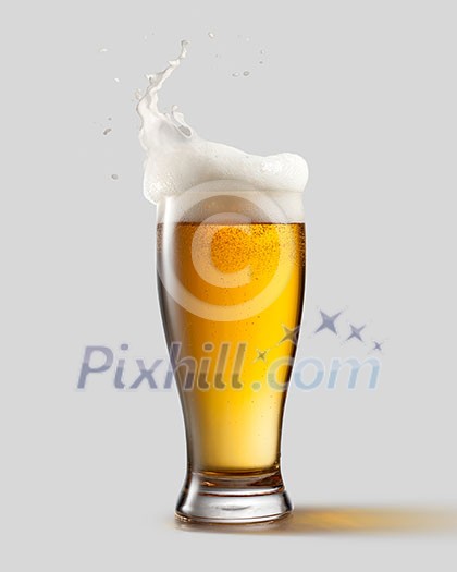 Frosty glass of light beer with foam and splashes, isolated on gray background Frosty glass of light beer with foam and splashes, isolated on gray background