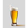 Frosty glass of light beer with foam and splashes, isolated on gray background