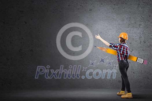 Young female engineer in hard hat with big pencil Young female engineer in hard hat with big pencil