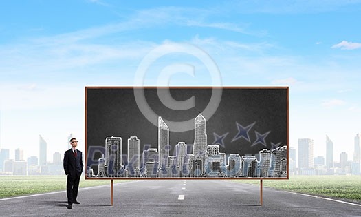 Young confident man wearing glasses standing near blackboard Young confident man wearing glasses standing near blackboard