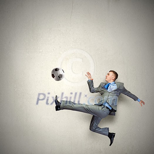 Businessman in suit hitting soccer ball in jump