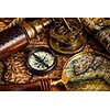 Travel geography navigation concept background - old vintage retro compass, sundial, magnifying glass and spyglass on ancient world map