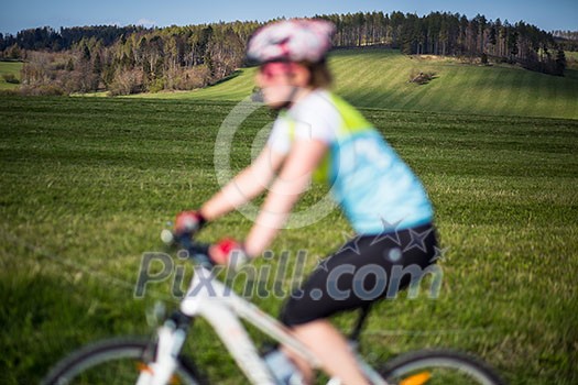 Female mountain biker out of focus with in focus landscape in the distance behind her Female mountain biker out of focus with in focus landscape in the distance behind her