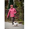 Senior woman walking her little dog on a city street; looking happy and relaxed (shallow DOF)