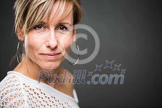 Portrait of a smiling middle aged caucasian woman against grey background (shallow DOF; color toned image)