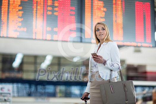 Young female passenger at the airport, using her tablet computer while waiting for her flight (color toned image)