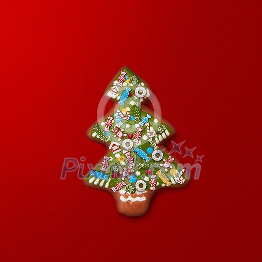 Christmas tree from ginger cookies with decorations on red background