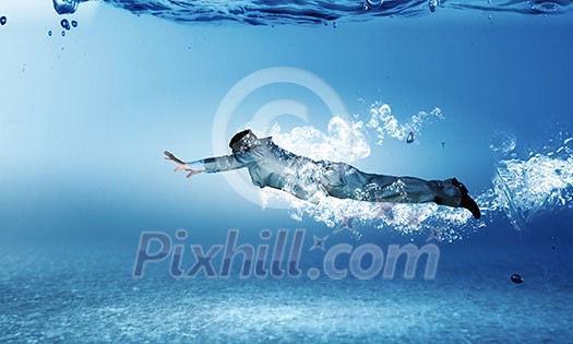 Young businessman in suit swimming under water