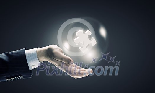 Close up of businessman holding jigsaw elements in palm Close up of businessman holding jigsaw elements in palm
