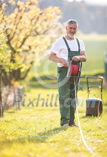 Senior man mowing the lawn in his garden (selective focus; shallow DOF)