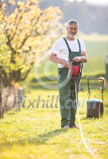 Senior man mowing the lawn in his garden (selective focus; shallow DOF) Senior man mowing the lawn in his garden (selective focus; shallow DOF)