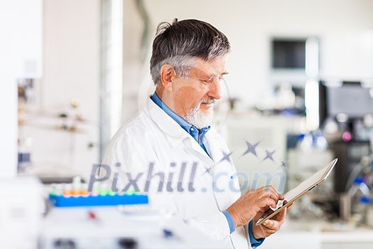 Senior doctor/scientist using his tablet computer at work (color toned image)