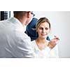 Optometry concept - pretty young woman having her eyes examined by an eye doctor/optometrist (color toned image; shallow DOF)