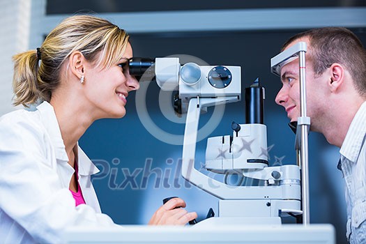 Optometry concept - handsome young man having his eyes examined by an eye doctor (color toned image; shallow DOF)