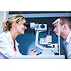 Optometry concept - handsome young man having his eyes examined by an eye doctor (color toned image; shallow DOF)