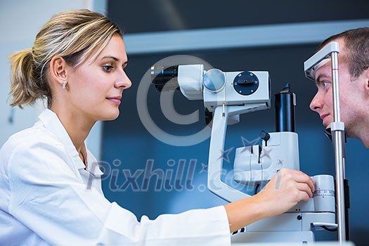 Optometry concept - handsome young man having his eyes examined by an eye doctor (color toned image; shallow DOF) Optometry concept - handsome young man having his eyes examined by an eye doctor (color toned image; shallow DOF)