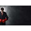 Young businessman in red boxing gloves on dark background