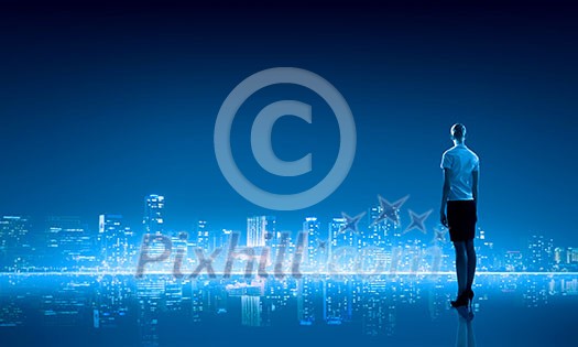 Businesswoman standing with back against night city panoramic view Businesswoman standing with back against night city panoramic view