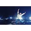 Young woman dancer jumping in spotlights on dark background