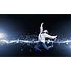 Young woman dancer jumping in spotlights on dark background